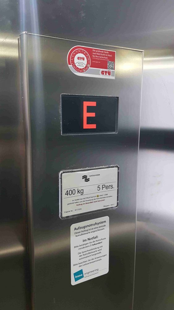 Ergoldsbach – Homelift nach Maschinenrichtlinie im Glasschacht<br> Barrierefreier Praxiszugang